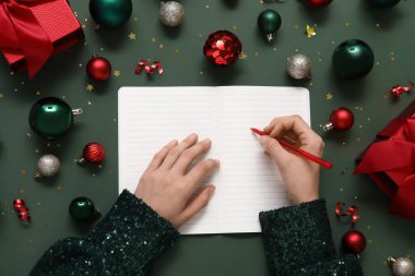 2025 yılını Noel dekoru ve yeşil arka planda hediyelerle geçiren bir kadın.