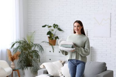 Evde bir yığın kalın kazağı olan genç bir kadın var.