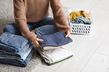 Genç bir kadın, elbiselerini katlıyor.