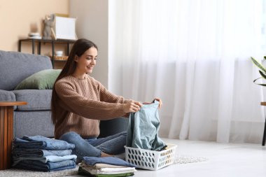 Genç bir kadın evde giysileri katlıyor.