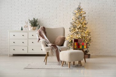 Oturma odasının içinde koltuk, parlayan Noel ağacı ve gelişmekte olan takvim.