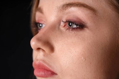 Siyah arka planda ağlayan genç kadın, yakın plan.