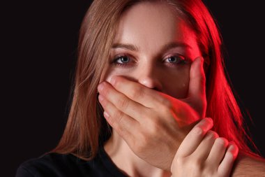 Adam, karanlık arka planda ağlayan kadının çenesini kapatıyor.