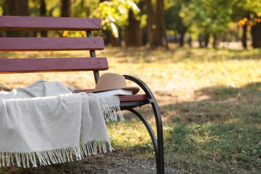 Sonbahar parkında kitap ve ekoseli şapka.