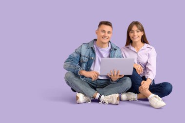 Leylak arka planında dizüstü bilgisayar kullanan genç çift