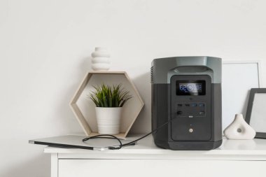 Dizüstü bilgisayarı olan taşınabilir elektrik santrali ve ışık duvarı yakınındaki çekmeceler.