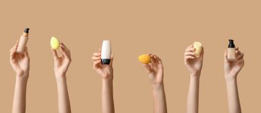 Bej arka planda makyajlı eller ve süngerler