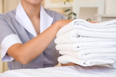 Otel odasında temiz havluları olan oda hizmetçisi.