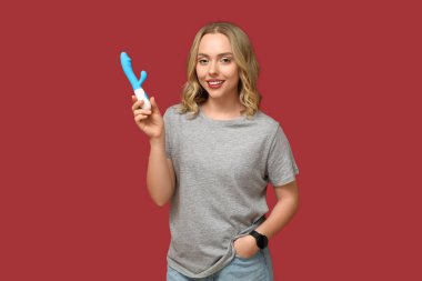 Kırmızı arka planda vibratörü olan güzel genç bir kadın.