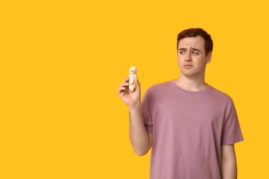 Sarı arka planda vibratörü olan duygusal genç bir adam.