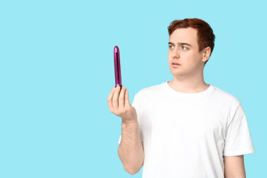 Mavi arka planda vibratörü olan yakışıklı bir genç.