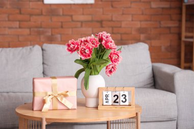 Çiçekli vazo, hediye kutusu ve takvim oturma odasındaki sehpanın üzerinde.