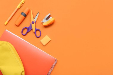 Turuncu arka planda kırtasiyeli defter ve kalem kutusu. Üst görünüm