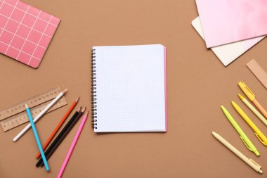 Kahverengi arka planda defter, cetvel ve kalemler. Üst görünüm