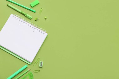 Yeşil arka planda defter ve keçeli kalemler. Üst görünüm