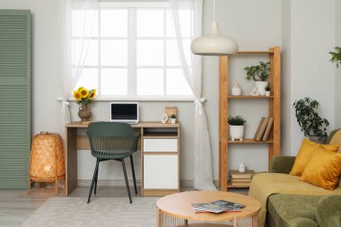 Çalışma odasının içinde, vazoda ve raf ünitesinde ayçiçekleri var.