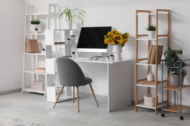 Bilgisayarlı modern çalışma alanı ve hafif ev ofisinde bir buket ayçiçeği.