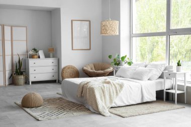 Çekmeceli, komodinli ve yataklı aydınlık yatak odasının modern iç mekanı.