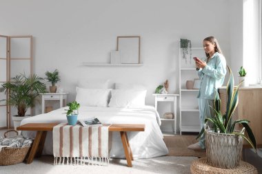 Evde cep telefonu kullanan pijamalı güzel bir kadın.