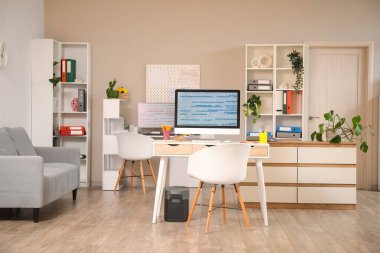 Masaları, kanepesi ve bitkileri olan programcı ofisinin içinde.