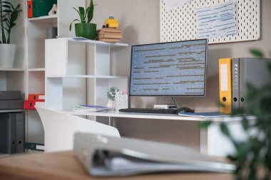 Ofisinde bilgisayar monitörü ve dizinleri olan programcı masası