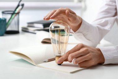 Ofisteki masada ampulü ve defteri olan iş kadını, yakın plan.