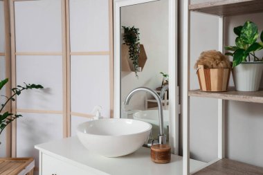 Lavabosu, aynası ve katlanabilir ekranı olan hafif banyonun içi.