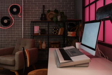 Podcaster 'ın iş yeri karanlık stüdyoda bilgisayar ve sentezleyici ile.