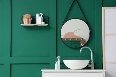 Lavabosu, aynası ve rafı olan bir banyo.