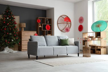 Japon Yeni Yıl kutlamaları için kanepe, köknar ağacı ve dekoru olan oturma odasının içinde.