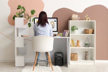 Ofisteki masada bilgisayarla çalışan kadın web tasarımcısı, arka görünüm