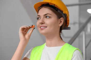 Kadın müteahhit kulak tıkaçları takıyor, yakın plan.