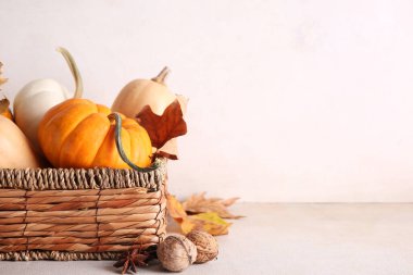 Beyaz arka planda taze balkabakları, yıldız anasonu, ceviz ve sonbahar yapraklarıyla dolu bir hasır kutu.