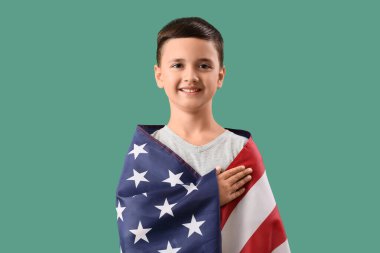 Amerikan bayrağı taşıyan küçük çocuk yeşil arka planda dua ediyor. Gaziler Günü kutlamaları