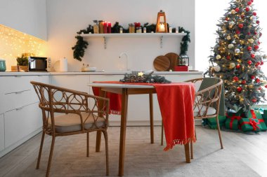 Mutfağın içinde tezgahlar, yemek masası ve Noel ağacı var.