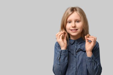 Gri arka planda tatlı çikolata şekerleri olan mutlu küçük kız