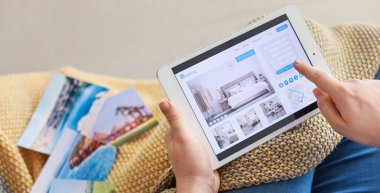Evindeki otelde tablet bilgisayarlı rezervasyon odası olan kadın.