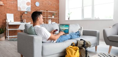 Bilgisayarlı bir adam evde online bilet ayırtıyor.