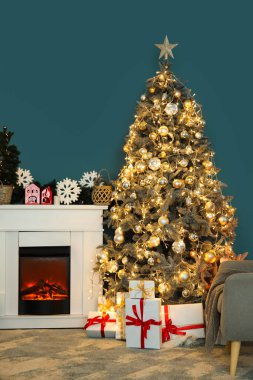 İçinde Noel ağacı, hediye kutuları, parlayan ışıklar, şömine ve koltuk olan oturma odası.