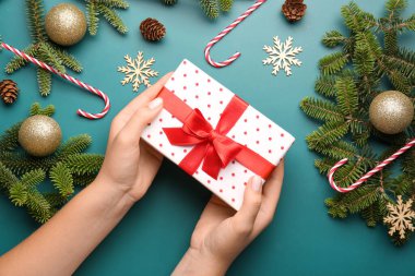 Hediye kutulu kadın elleri ve mavi arka planda Noel ağacı dalları