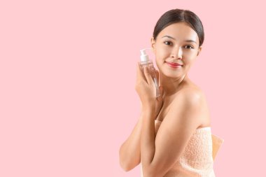 Pembe arka planda bir şişe mikiler suyu olan genç Asyalı kadın.