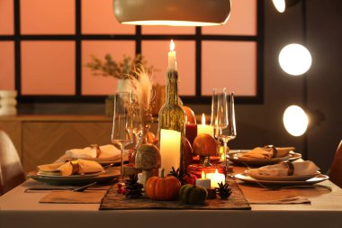 Akşamki Şükran Günü için yanan mumlar, balkabakları ve tebrik kartları olan şenlik masası.