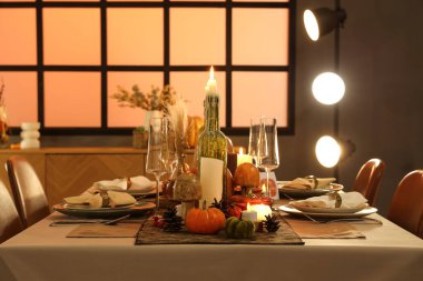 Akşamki Şükran Günü yemeği için yanan mumlar, balkabakları ve tebrik kartları olan güzel bir masa.