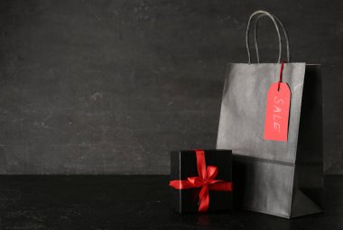 Koyu renk grunge masasında alışveriş çantası ve hediye kutusu. Kara Cuma indirimi