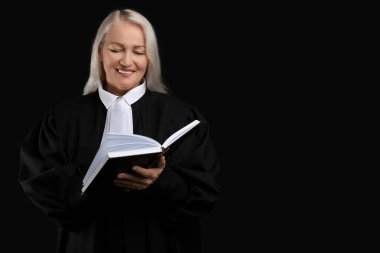 Siyah arka plan kitabı olan olgun bir kadın yargıç.