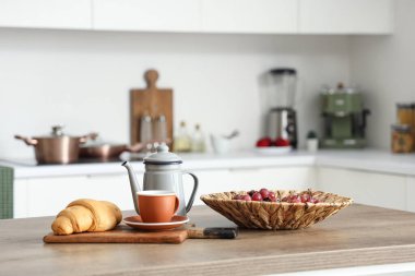 Modern mutfakta üzümlü mutfak masası, çay ve kruvasan.
