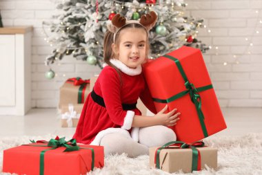 Noel Baba kostümlü, Noel arifesinde evde hediye kutularıyla sevimli küçük bir kız.