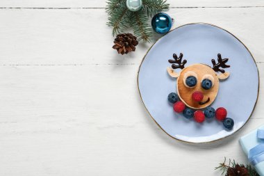 Beyaz ahşap masada geyik şeklinde krep tabağı. Noel kutlaması