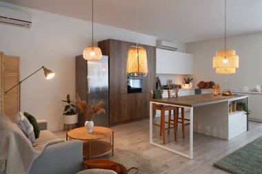 Gri kanepesi, adası ve parlayan lambaları olan modern açık uzay mutfağı.