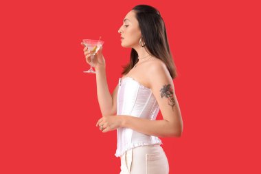 Kırmızı arka planda martinisi olan güzel bir kadın.